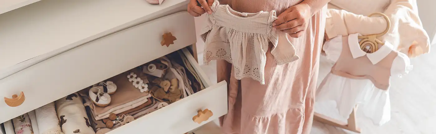 Foto einer Frau, die Babykleidung hält